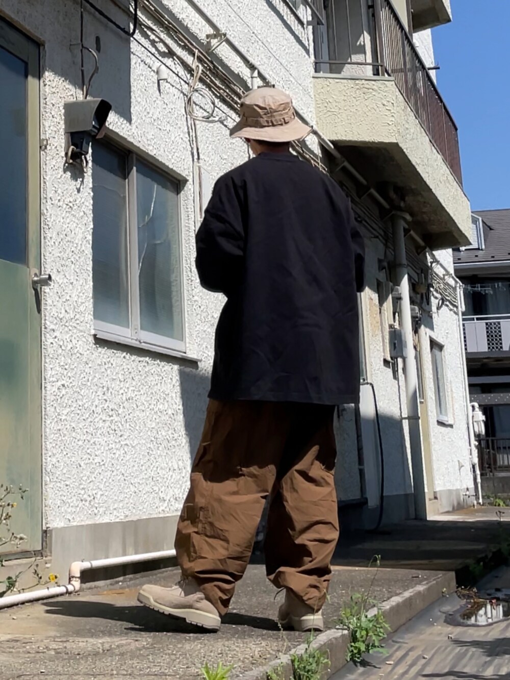 ベージュ系のブーツ、ブラウン系のカーゴパンツ、ブラック系のTシャツ/カットソーを着用したメンズの春コーディネートの2枚目の写真