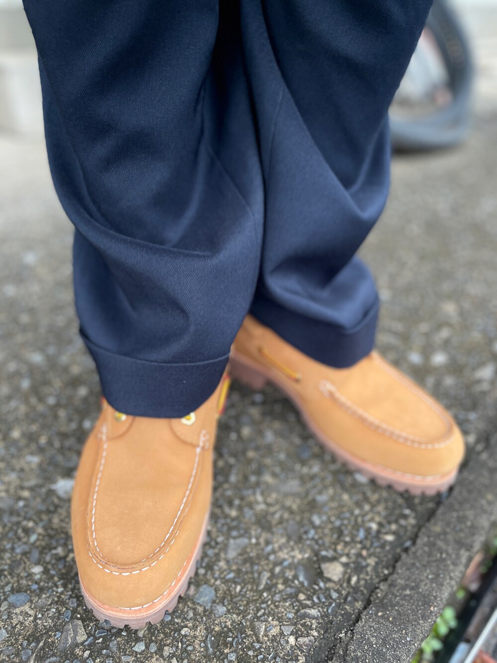 ブラウン系のニット/セーター、ブルー系のスラックス、イエロー系のモカシン/デッキシューズを着用したメンズの秋コーディネートの3枚目の写真