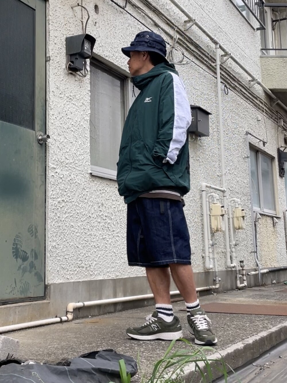 グリーン系のスニーカー、ブルー系のデニムパンツ、グリーン系のマウンテンパーカーを着用したメンズの春コーディネートの3枚目の写真