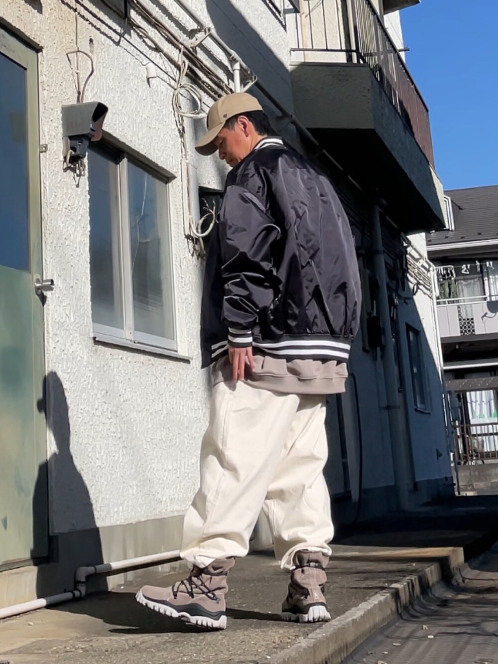 ブラウン系のスニーカー、ホワイト系のデニムパンツ、ベージュ系のスウェットを着用したメンズの春コーディネートの2枚目の写真