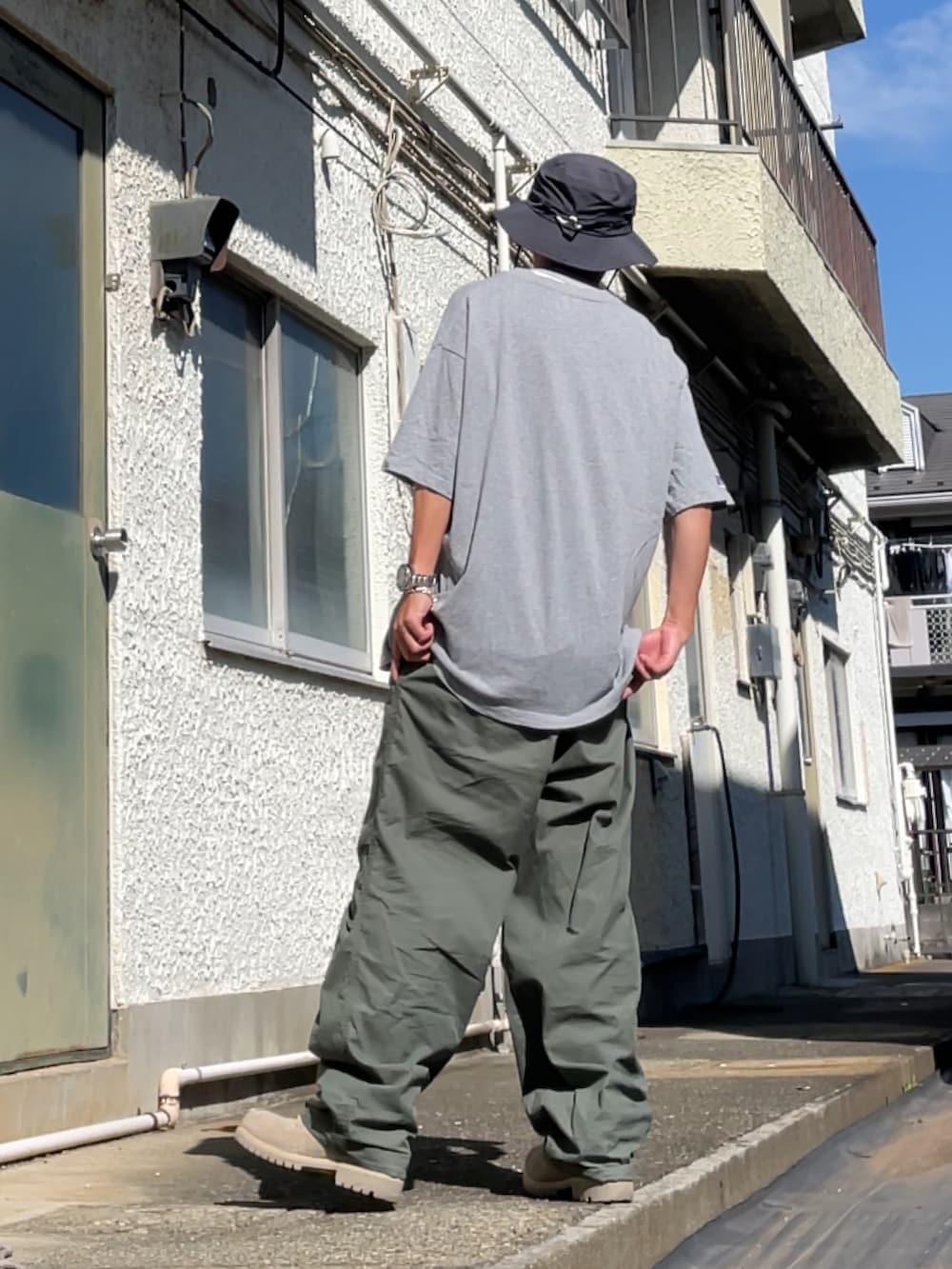 グレー系のTシャツ/カットソー、グリーン系のパンツ、ベージュ系のブーツを着用したメンズの秋コーディネートの2枚目の写真