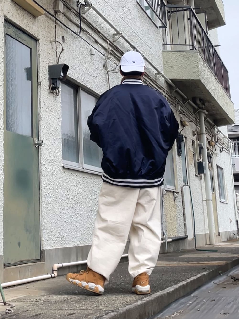 ブラウン系のスニーカー、ホワイト系のデニムパンツ、ブルー系のブルゾンを着用したメンズの冬コーディネートの2枚目の写真