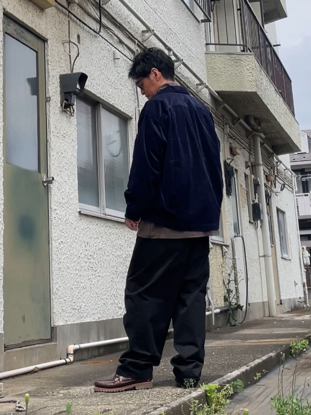 ブラック系のチノパンツ、ブラウン系のTシャツ/カットソー、ブラウン系のモカシン/デッキシューズを着用したメンズの春コーディネートの2枚目の写真