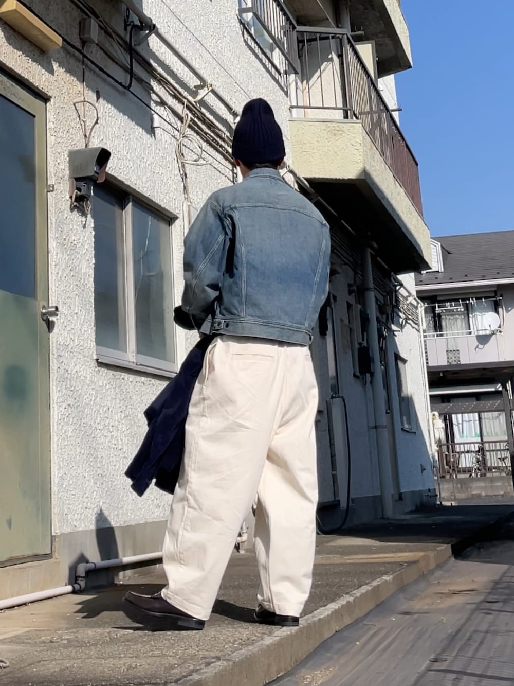 ブルー系のデニムジャケット、ブラウン系のローファー、ホワイト系のデニムパンツを着用したメンズの冬コーディネートの2枚目の写真