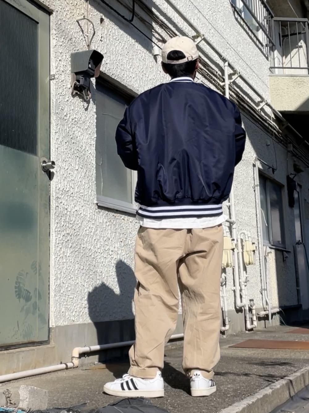 ホワイト系のスニーカー、ベージュ系のその他パンツ、ブルー系のブルゾンを着用したメンズの秋コーディネートの2枚目の写真