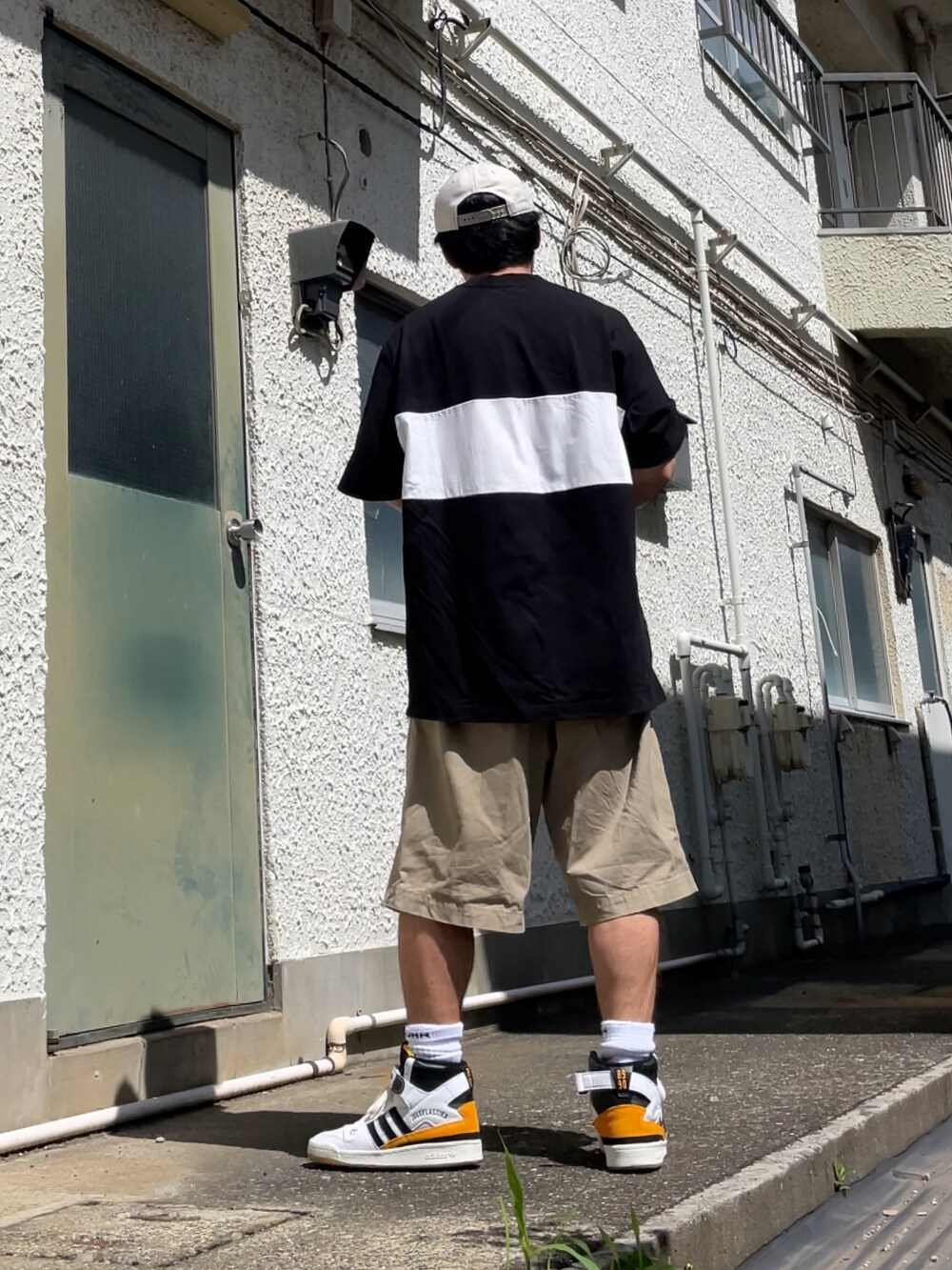 ホワイト系のスニーカー、ベージュ系のチノパンツ、ブラック系のTシャツ/カットソーを着用したメンズの夏コーディネートの2枚目の写真