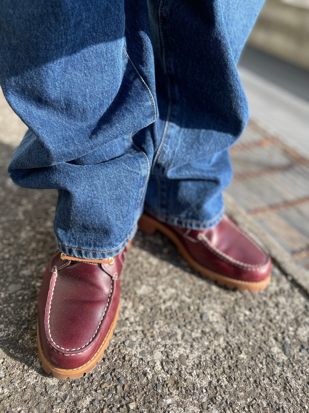 ベージュ系のステンカラーコート、ブルー系のデニムパンツ、ブラウン系のニット/セーターを着用したメンズの春コーディネートの3枚目の写真