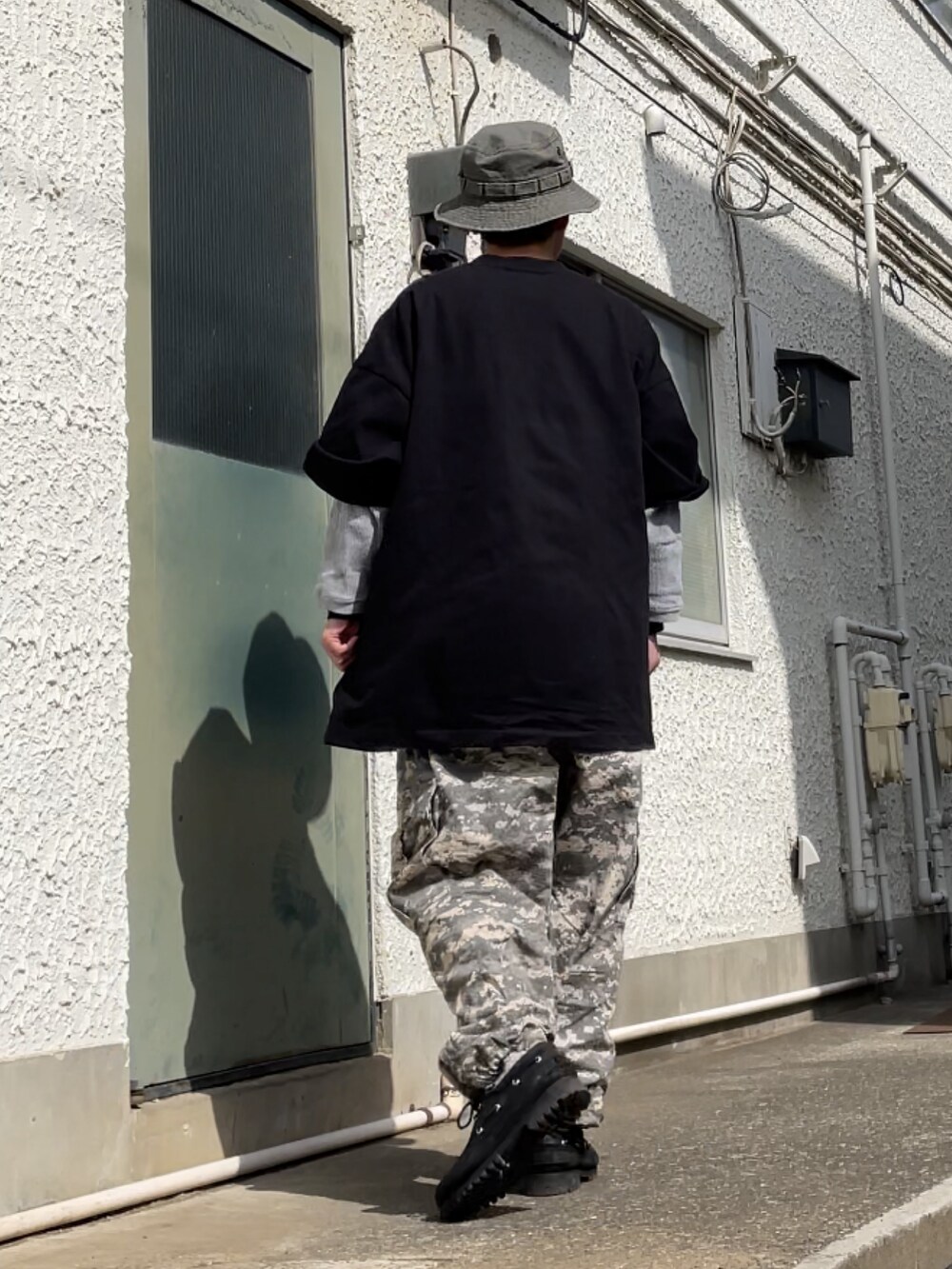 ブラック系のその他シューズ、グリーン系のカーゴパンツ、ブラック系のTシャツ/カットソーを着用したメンズの春コーディネートの2枚目の写真