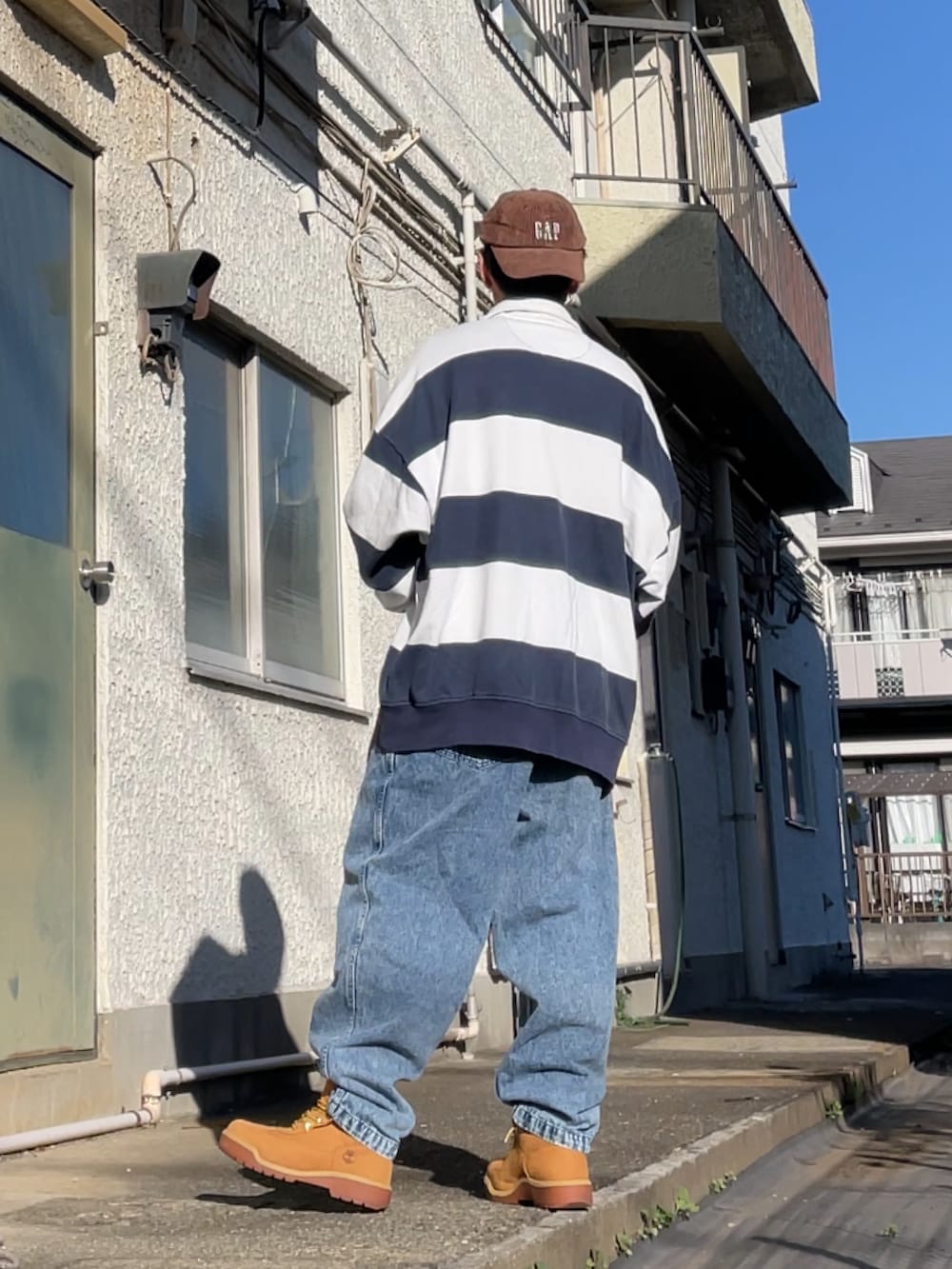 ホワイト系のスウェット、ブルー系のデニムパンツ、イエロー系のブーツを着用したメンズの冬コーディネートの2枚目の写真