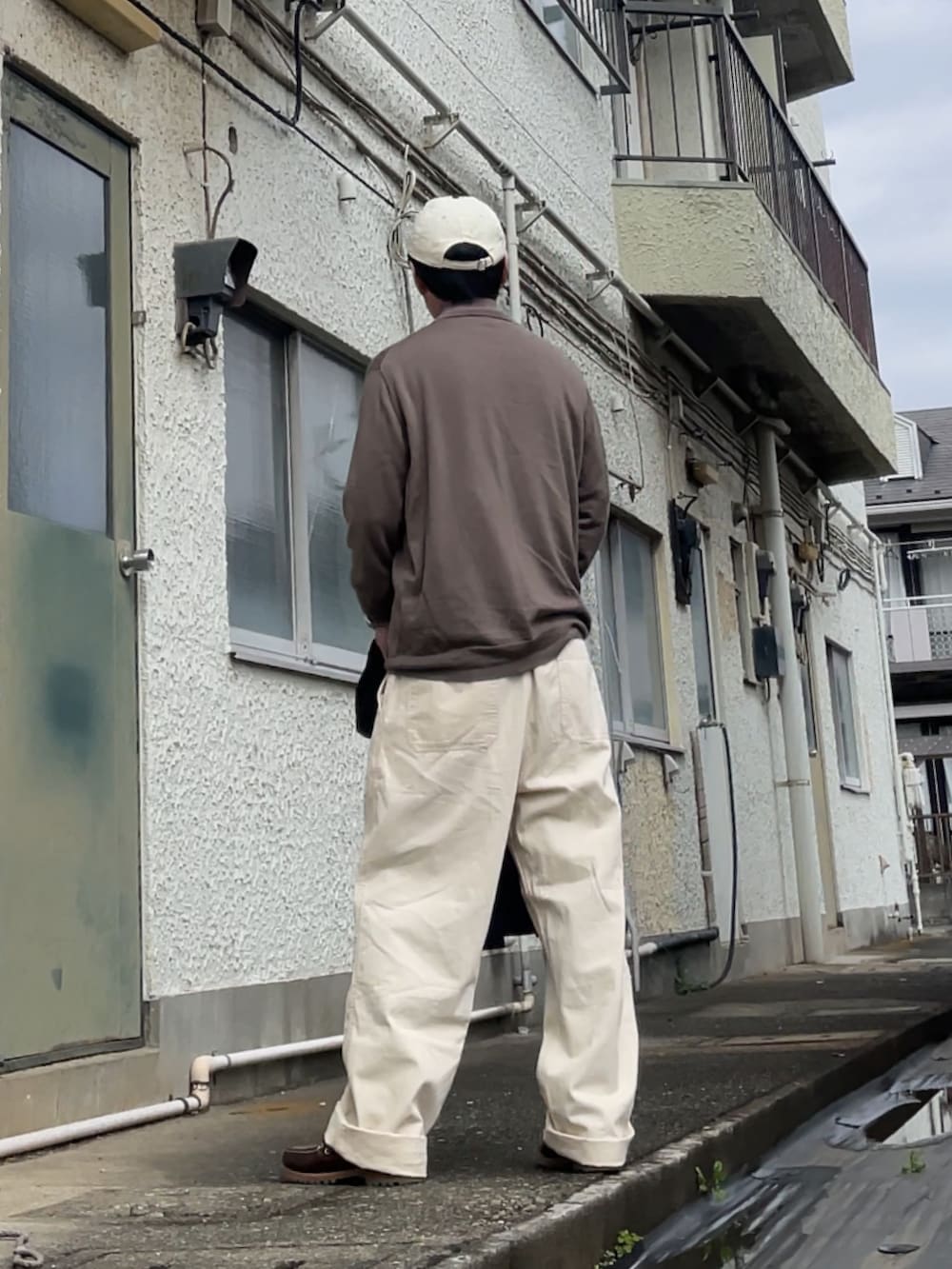 ブラウン系のニット/セーター、ブラウン系のモカシン/デッキシューズ、ホワイト系のパンツを着用したメンズの春コーディネートの2枚目の写真