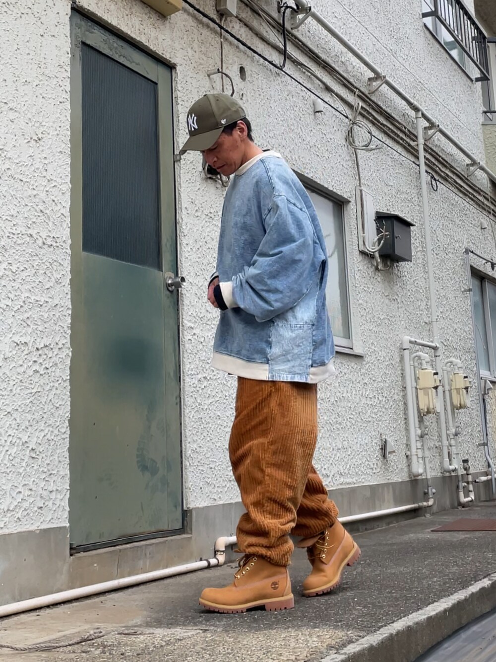 イエロー系のブーツ、ブラウン系のその他パンツ、ブルー系のトップスを着用したメンズの冬コーディネートの2枚目の写真