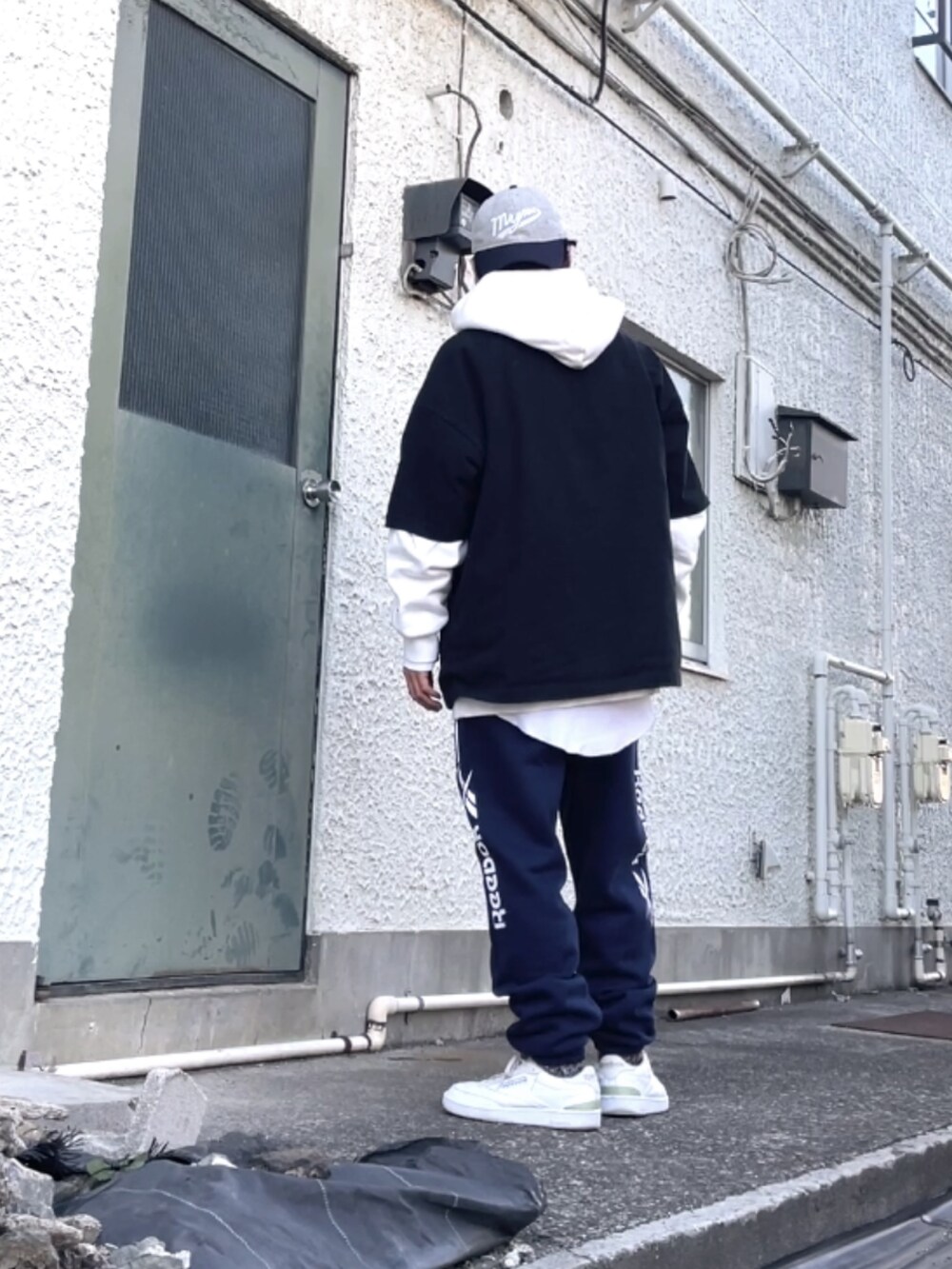 ホワイト系のスニーカー、ブルー系のスウェットパンツ、ブラック系のTシャツ/カットソーを着用したメンズの冬コーディネートの2枚目の写真