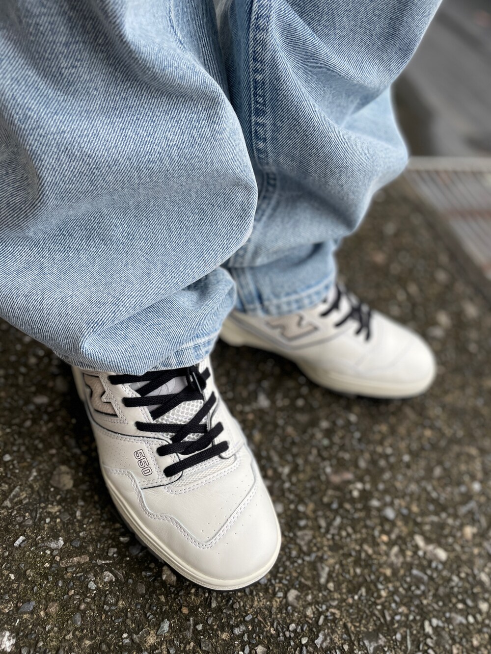 ホワイト系のスニーカー、ブルー系のデニムパンツ、ブラック系のTシャツ/カットソーを着用したメンズの秋コーディネートの3枚目の写真