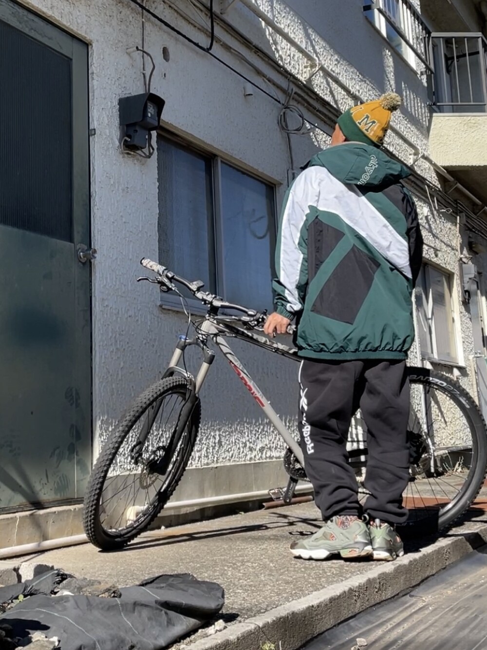 グリーン系のスニーカー、ブラック系のスウェットパンツ、グリーン系のマウンテンパーカーを着用したメンズの秋コーディネートの3枚目の写真