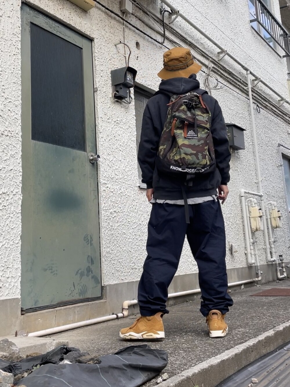 ブラウン系のスニーカー、ブルー系のチノパンツ、その他のバックパック/リュックを着用したメンズの秋コーディネートの2枚目の写真