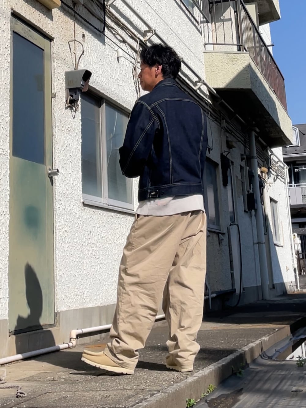 ベージュ系のチノパンツ、ベージュ系のモカシン/デッキシューズ、ブルー系のデニムジャケットを着用したメンズの春コーディネートの2枚目の写真