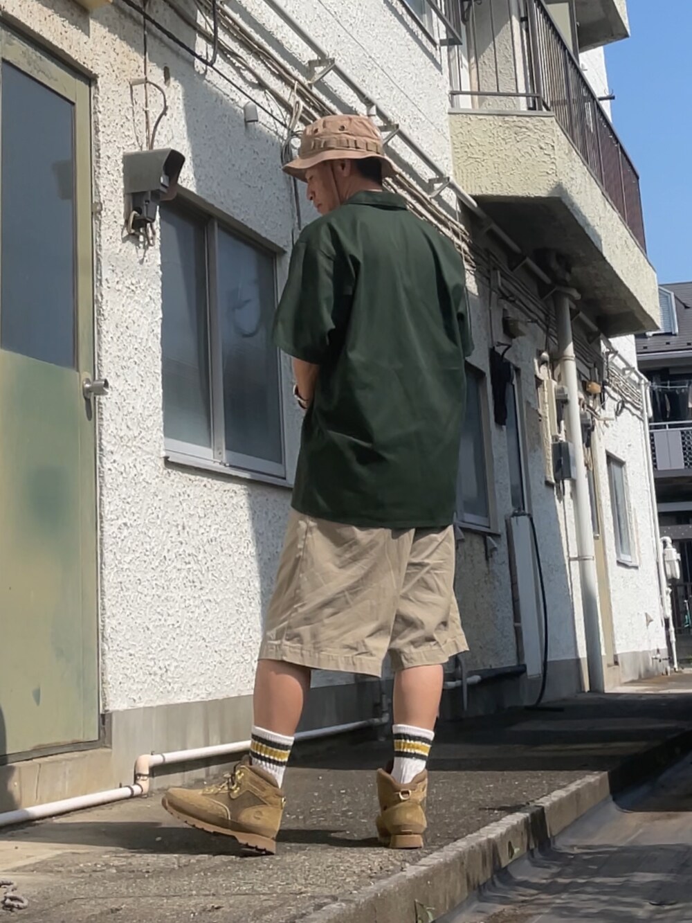 グリーン系のシャツ/ブラウス、ベージュ系のチノパンツ、ベージュ系のブーツを着用したメンズの夏コーディネートの2枚目の写真