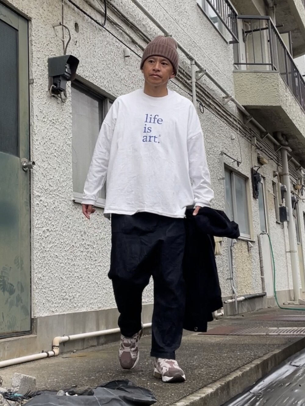 ブラウン系のスニーカー、ブラック系のデニムパンツ、ホワイト系のTシャツ/カットソーを着用したメンズの秋コーディネートの2枚目の写真