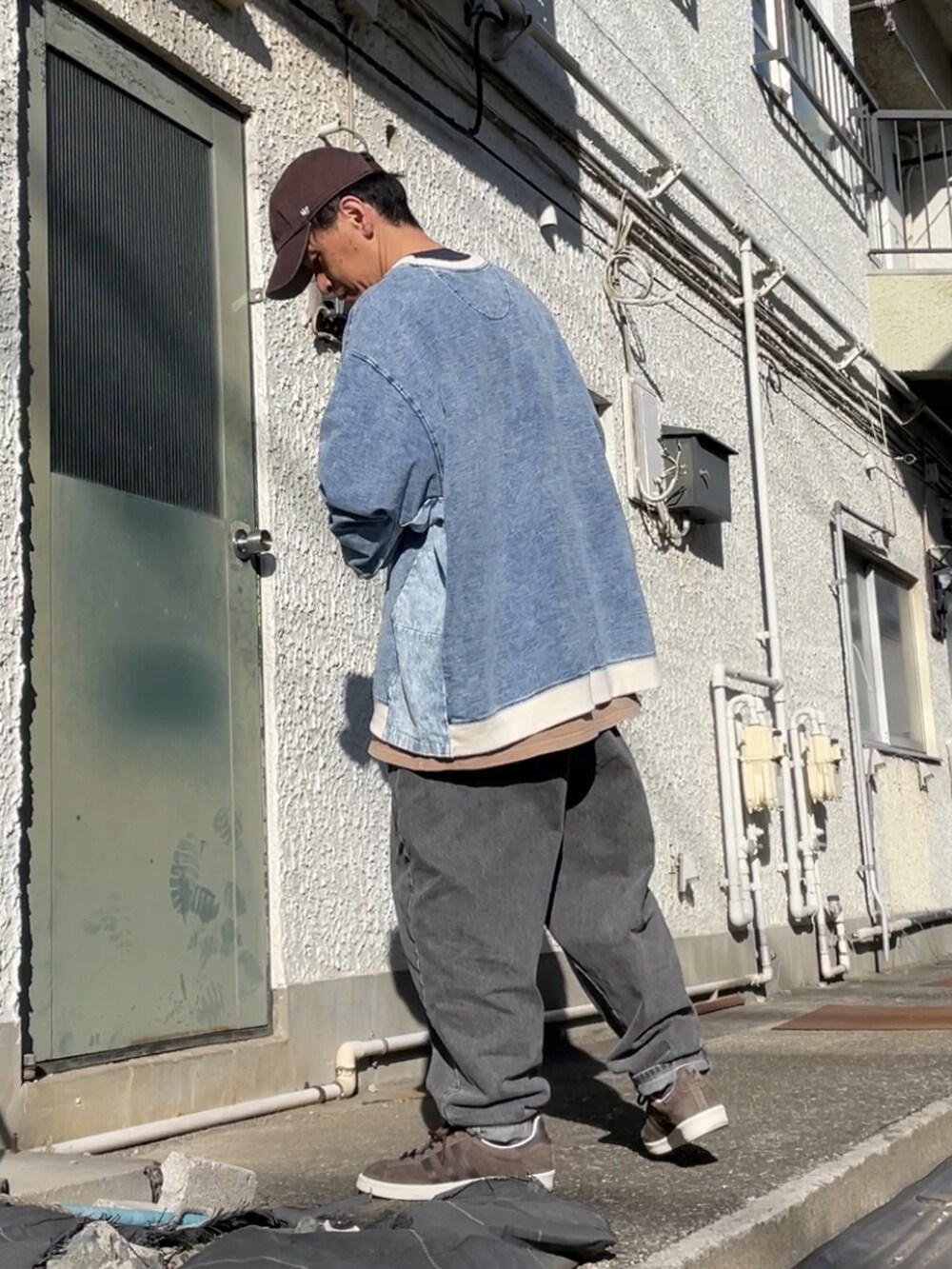 ブラウン系のスニーカー、ブラック系のデニムパンツ、ブルー系のトップスを着用したメンズの冬コーディネートの2枚目の写真