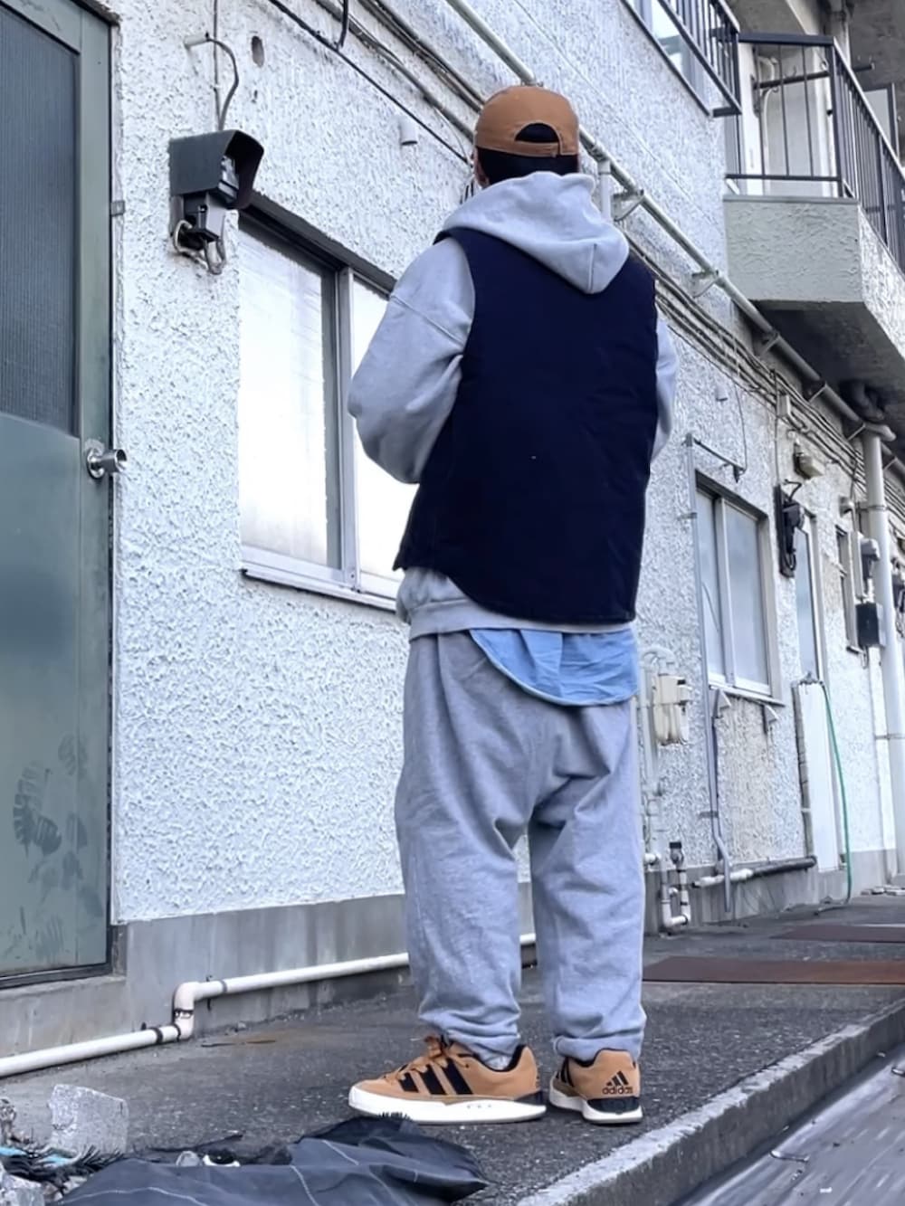 ブラウン系のスニーカー、グレー系のその他パンツ、ブルー系のベストを着用したメンズの秋コーディネートの2枚目の写真