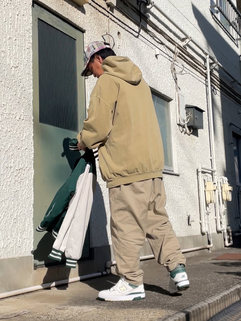 ホワイト系のスニーカー、ベージュ系のチノパンツ、グリーン系のパーカーを着用したメンズの冬コーディネートの2枚目の写真