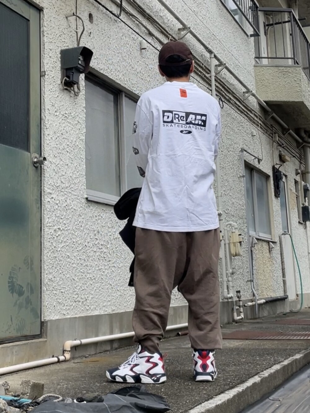 ホワイト系のスニーカー、ブラウン系のパンツ、ホワイト系のTシャツ/カットソーを着用したメンズの秋コーディネートの2枚目の写真