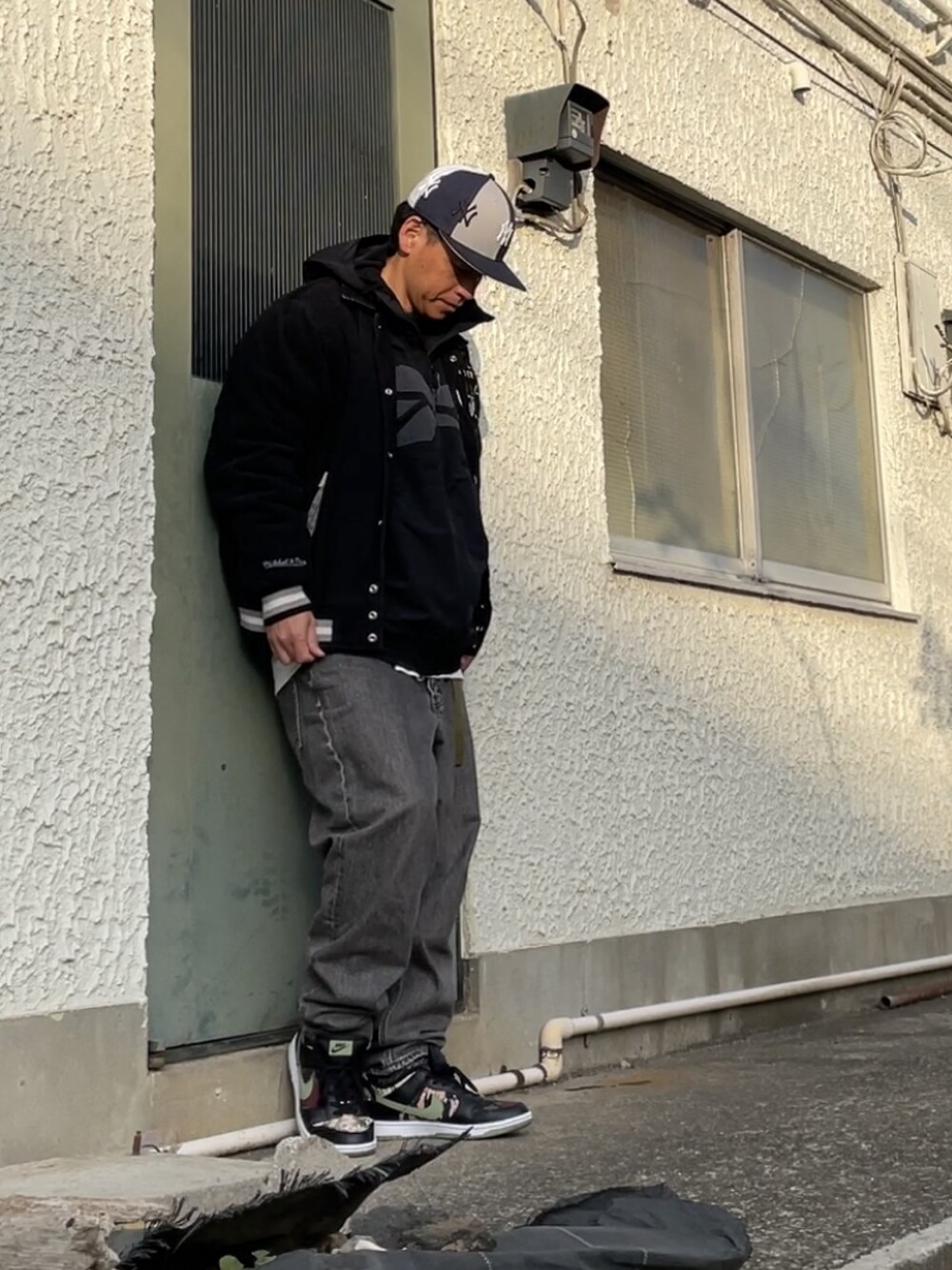ブラック系のスニーカー、ブラック系のデニムパンツ、ブラック系のスタジャンを着用したメンズの冬コーディネートの3枚目の写真