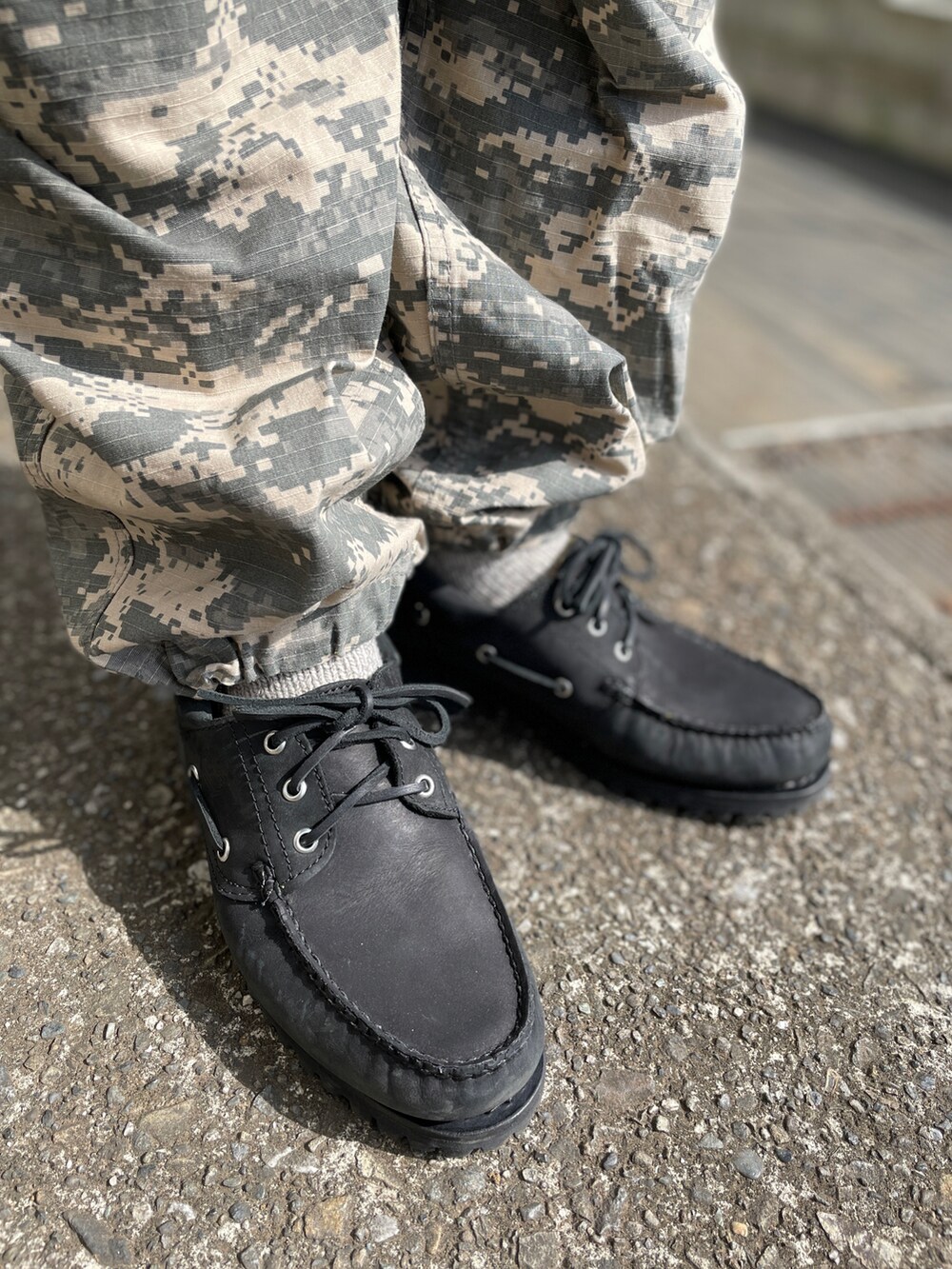 ブラック系のその他シューズ、グリーン系のカーゴパンツ、ブラック系のTシャツ/カットソーを着用したメンズの春コーディネートの3枚目の写真