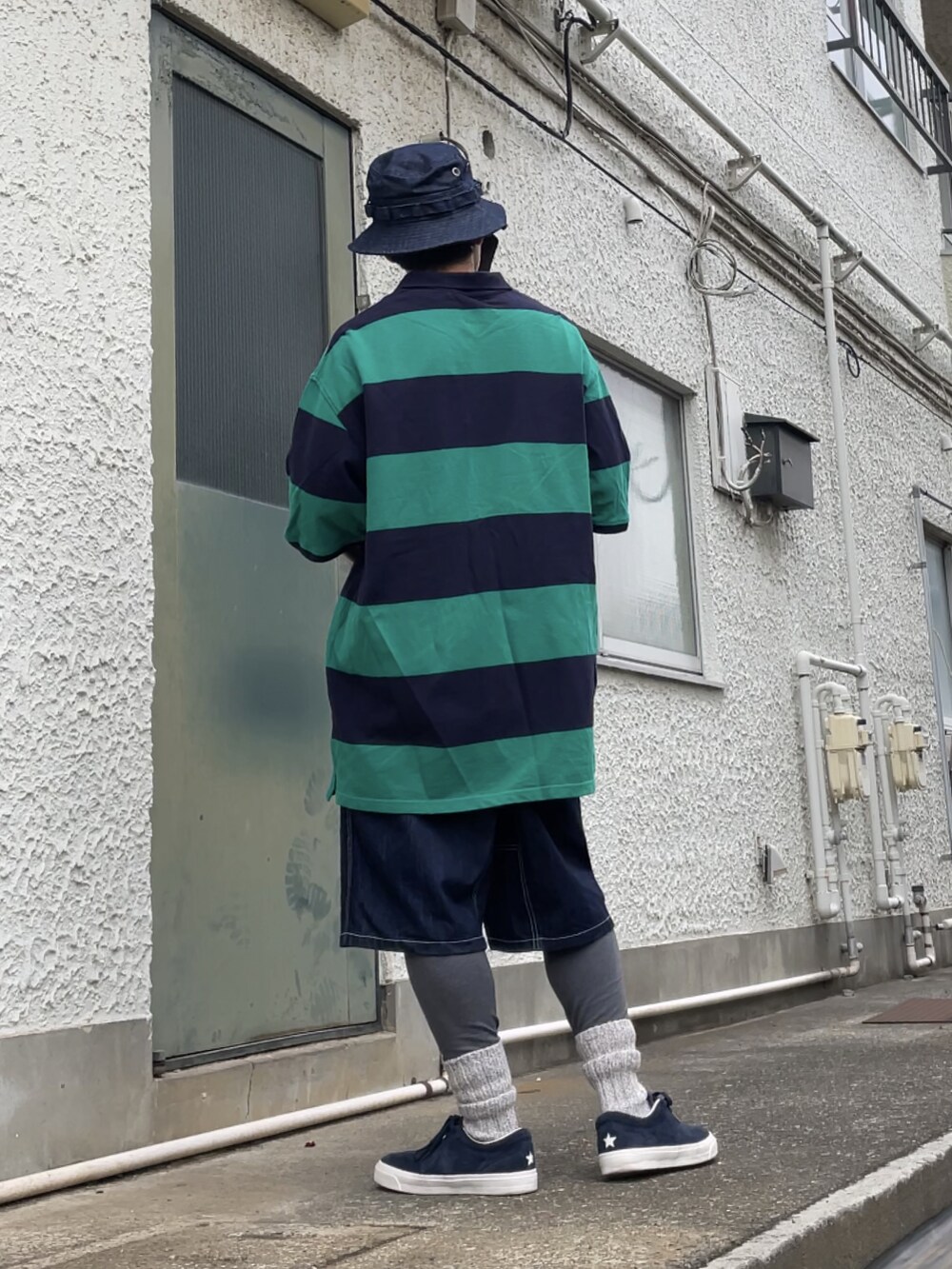 ブルー系のスニーカー、ブルー系のデニムパンツ、グリーン系のポロシャツを着用したメンズの春コーディネートの2枚目の写真