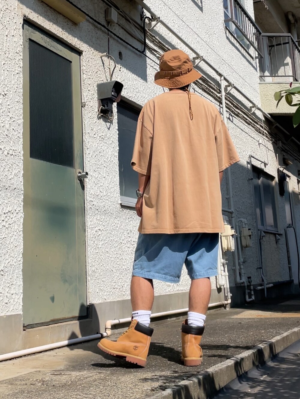 イエロー系のブーツ、ブルー系のその他パンツ、ベージュ系のTシャツ/カットソーを着用したメンズの秋コーディネートの2枚目の写真