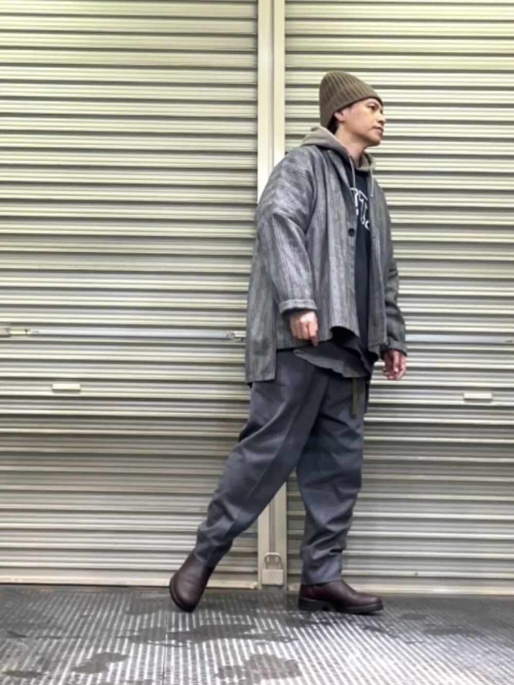 ブラウン系のブーツ、グレー系のスラックス、ブラック系のテーラードジャケットを着用したメンズの冬コーディネートの2枚目の写真