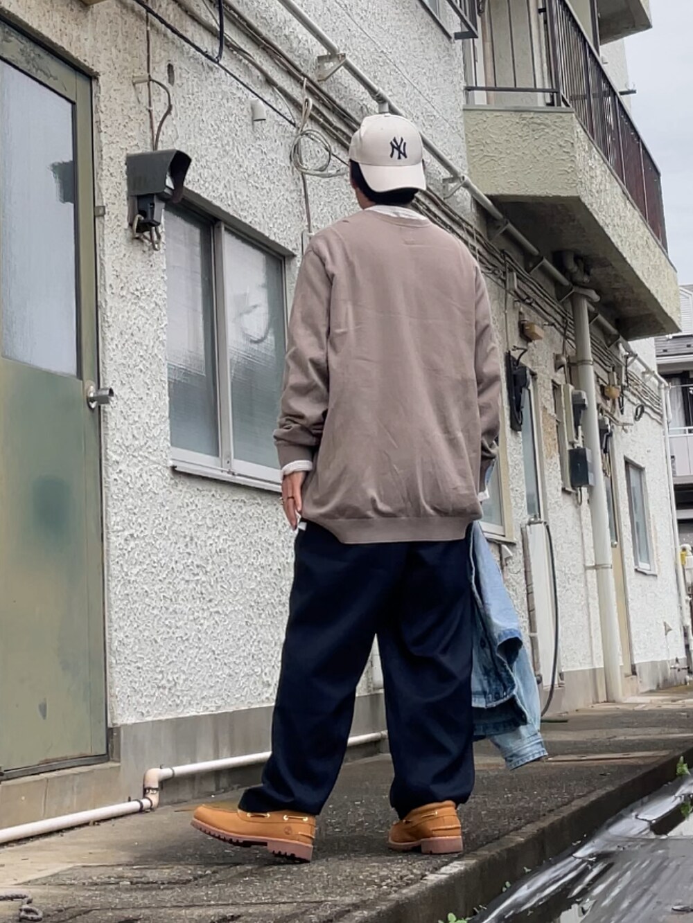 ブラウン系のニット/セーター、ブルー系のスラックス、イエロー系のモカシン/デッキシューズを着用したメンズの秋コーディネートの2枚目の写真