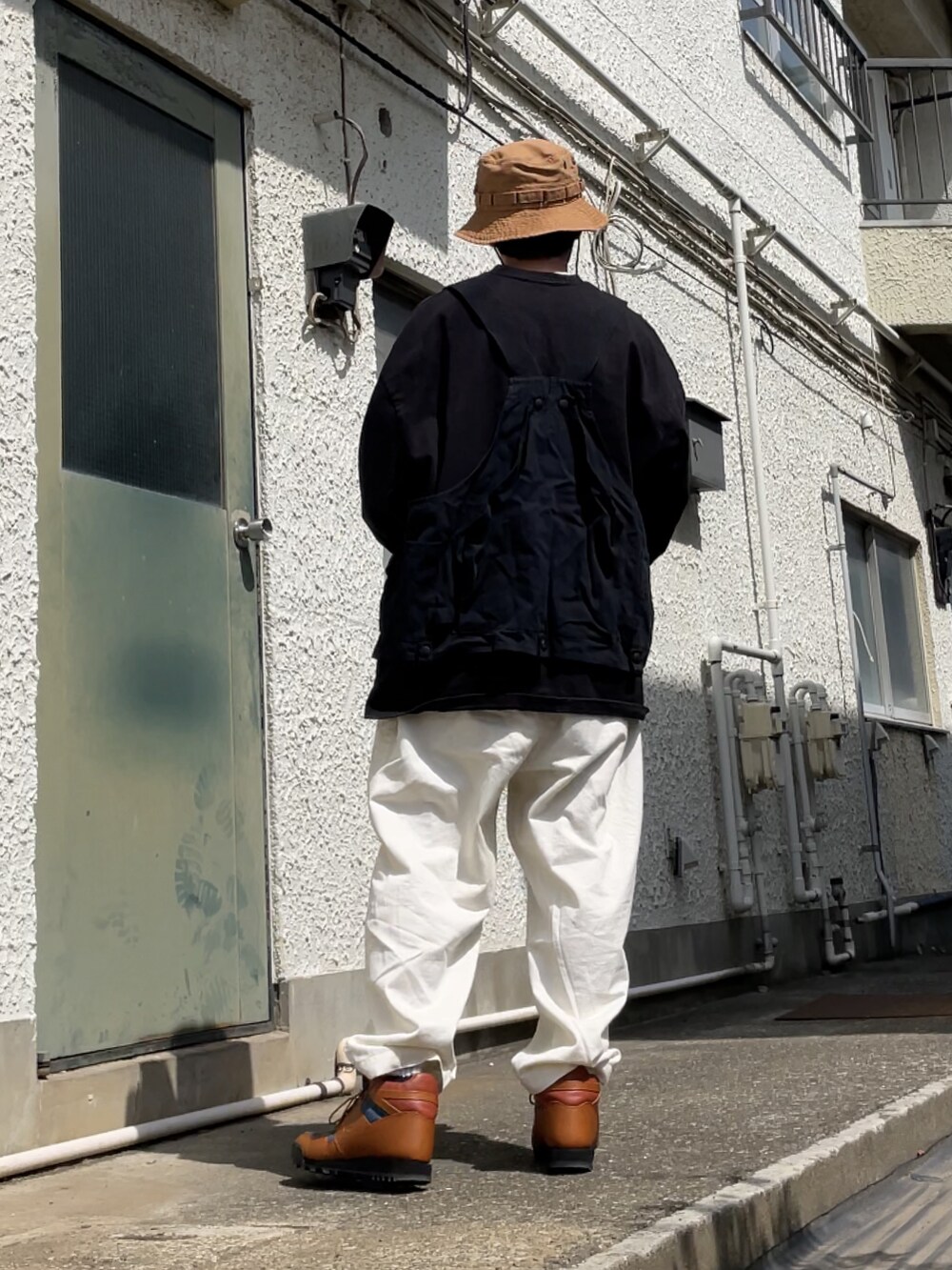 ブラウン系のスニーカー、ホワイト系のチノパンツ、ブラック系のベストを着用したメンズの春コーディネートの2枚目の写真