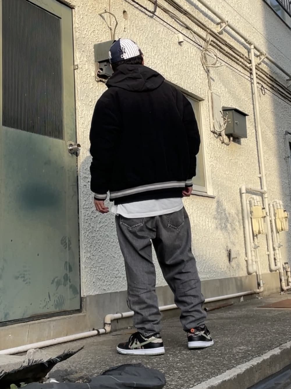 ブラック系のスニーカー、ブラック系のデニムパンツ、ブラック系のスタジャンを着用したメンズの冬コーディネートの4枚目の写真