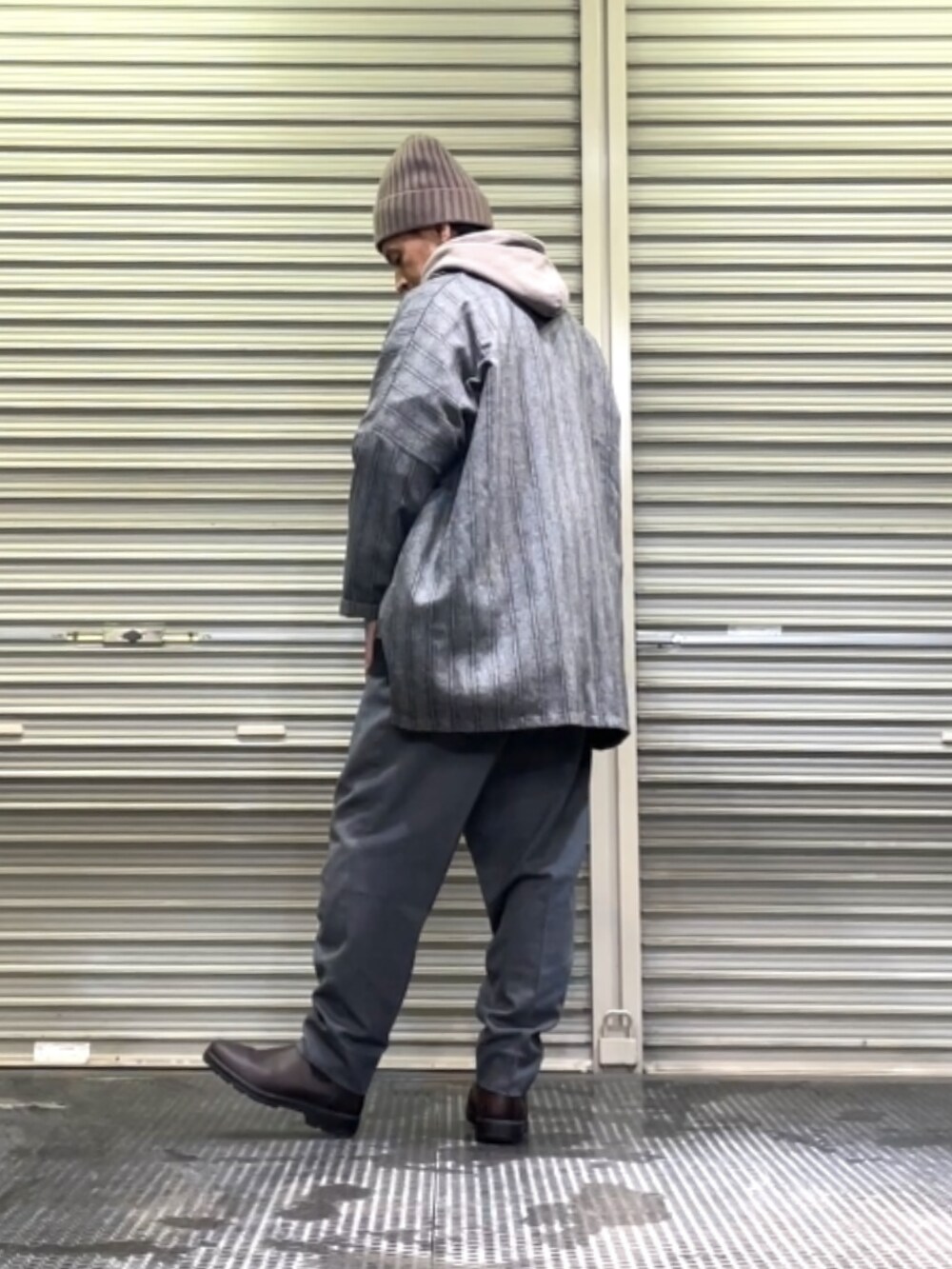 ブラウン系のブーツ、グレー系のスラックス、ブラック系のテーラードジャケットを着用したメンズの冬コーディネートの3枚目の写真