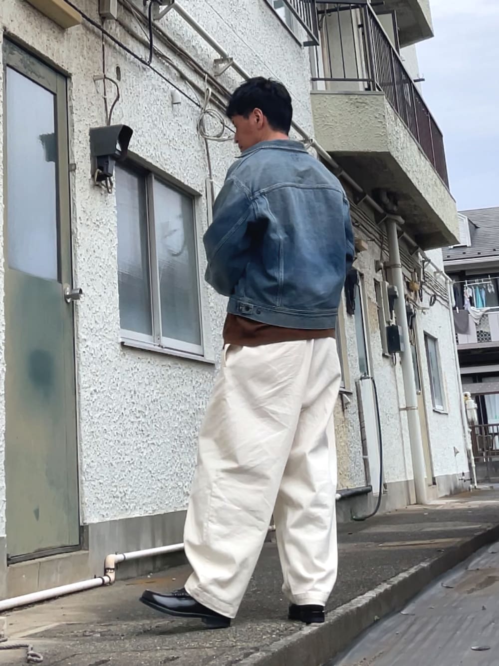 ブルー系のデニムジャケット、ブラウン系のローファー、ホワイト系のデニムパンツを着用したメンズの春コーディネートの2枚目の写真