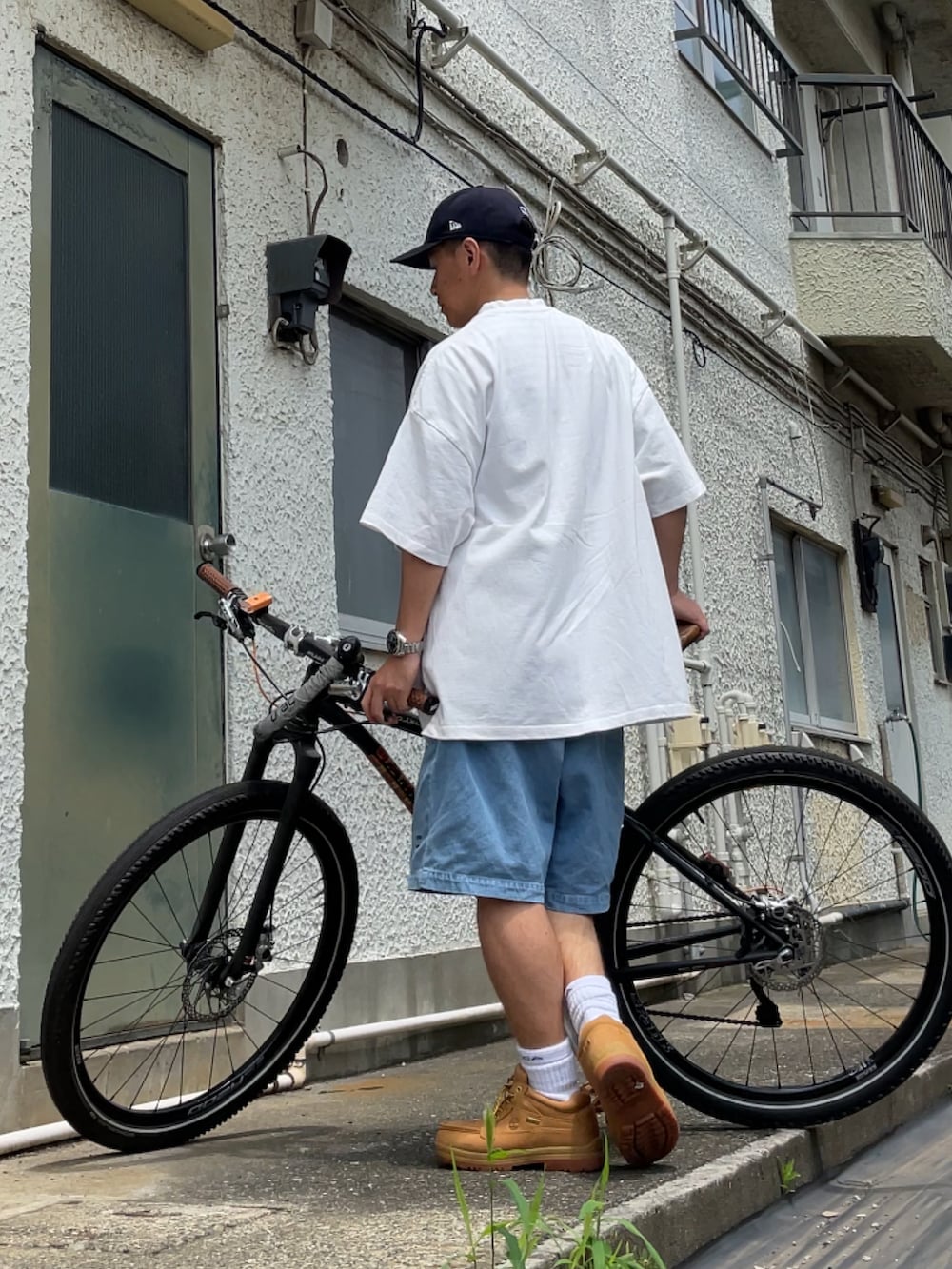 イエロー系のブーツ、ブルー系のその他パンツ、ホワイト系のTシャツ/カットソーを着用したメンズの夏コーディネートの2枚目の写真