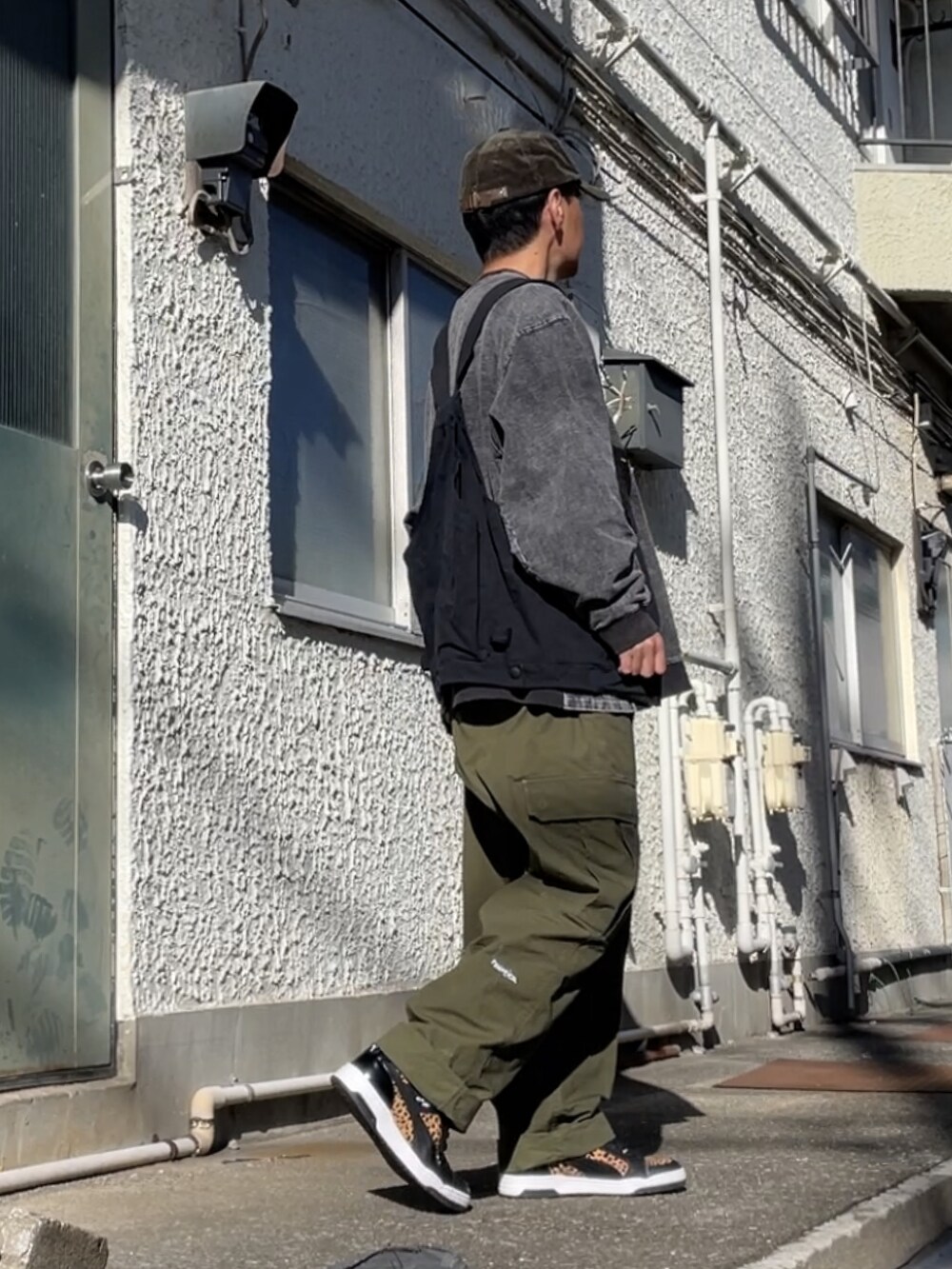 ブラック系のスニーカー、グリーン系のカーゴパンツ、ブラック系のベストを着用したメンズの冬コーディネートの2枚目の写真