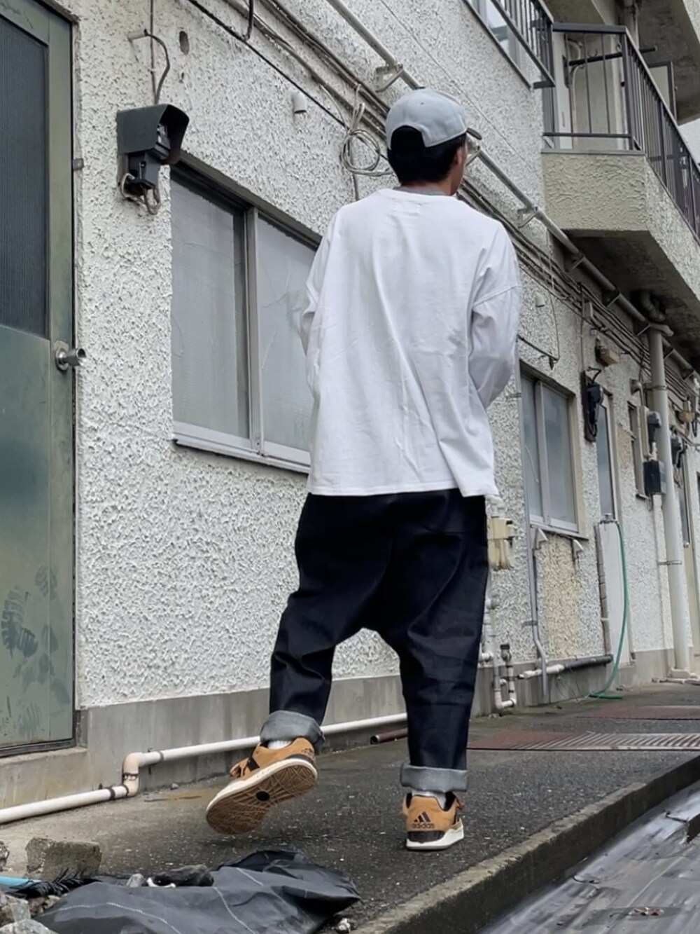 ブラウン系のスニーカー、ブラック系のデニムパンツ、ホワイト系のTシャツ/カットソーを着用したメンズの秋コーディネートの2枚目の写真