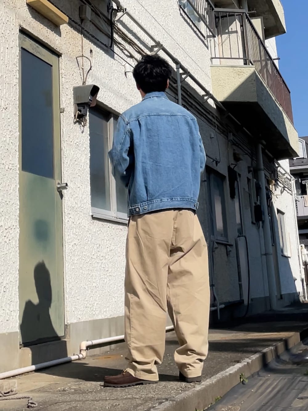 ブルー系のデニムジャケット、ベージュ系のチノパンツ、ブラウン系のブーツを着用したメンズの春コーディネートの2枚目の写真