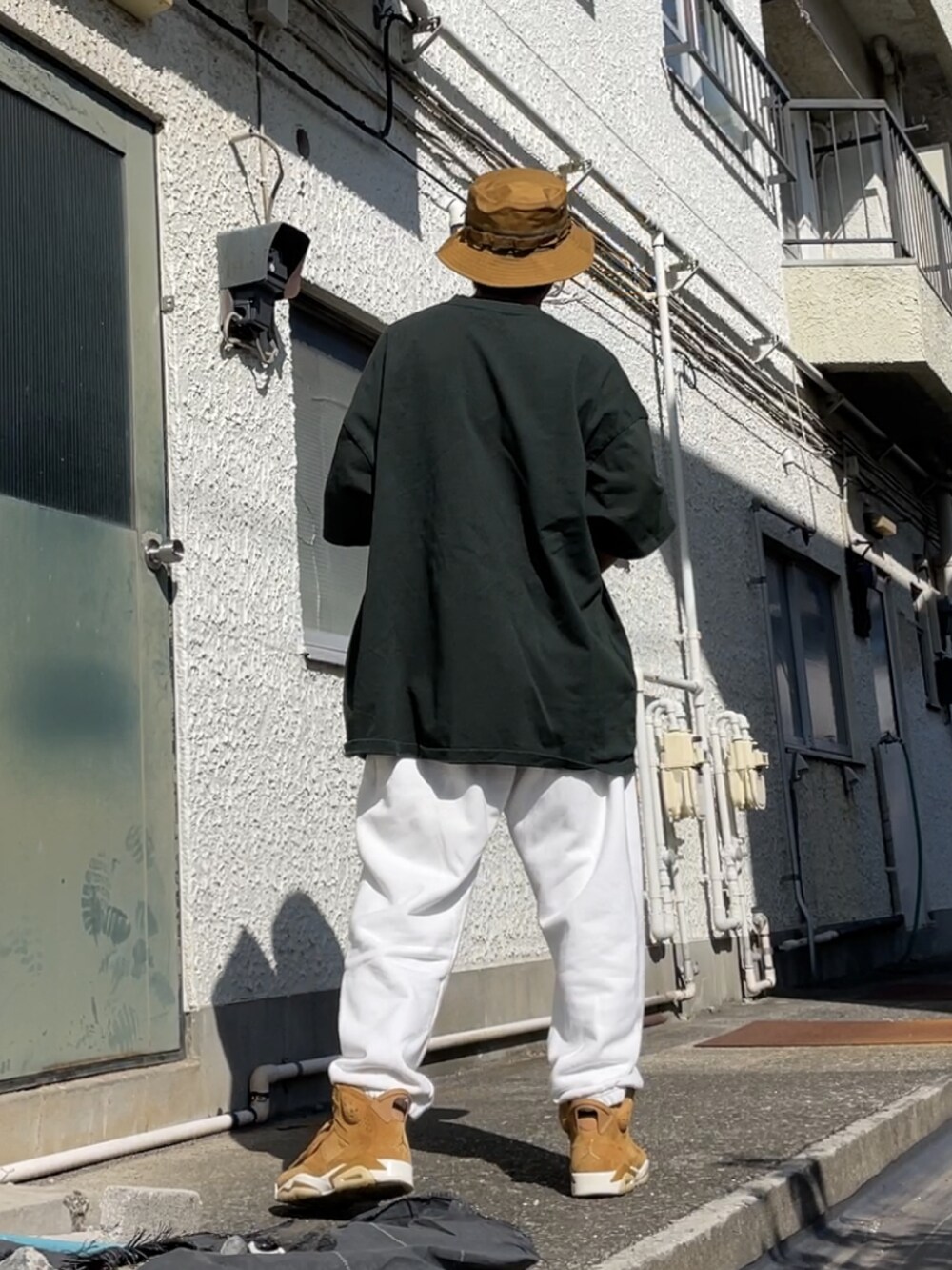 ブラウン系のスニーカー、ホワイト系のその他パンツ、グリーン系のTシャツ/カットソーを着用したメンズの秋コーディネートの2枚目の写真