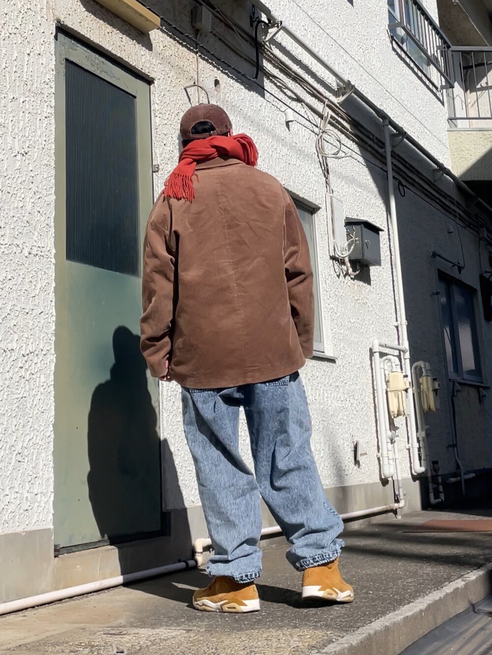 ブラウン系のスニーカー、ブルー系のデニムパンツ、イエロー系のニット/セーターを着用したメンズの春コーディネートの2枚目の写真