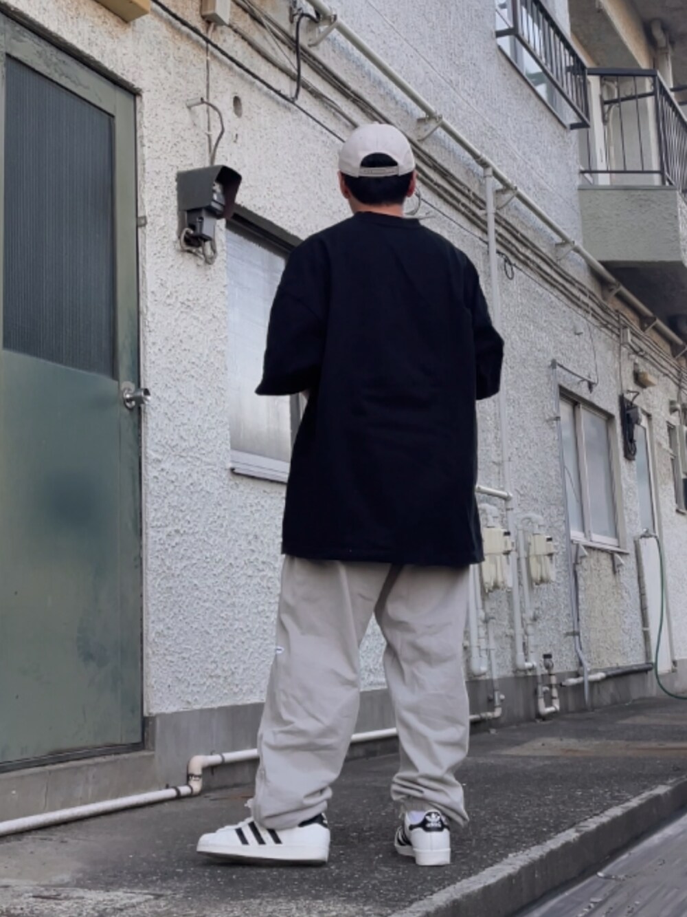 ホワイト系のスニーカー、グレー系のその他パンツ、ブラック系のTシャツ/カットソーを着用したメンズの春コーディネートの2枚目の写真