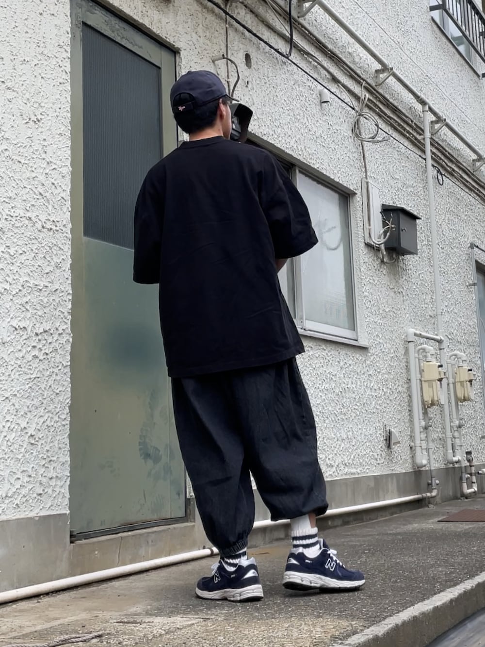 ブルー系のスニーカー、ブラック系のデニムパンツ、ブラック系のTシャツ/カットソーを着用したメンズの夏コーディネートの2枚目の写真