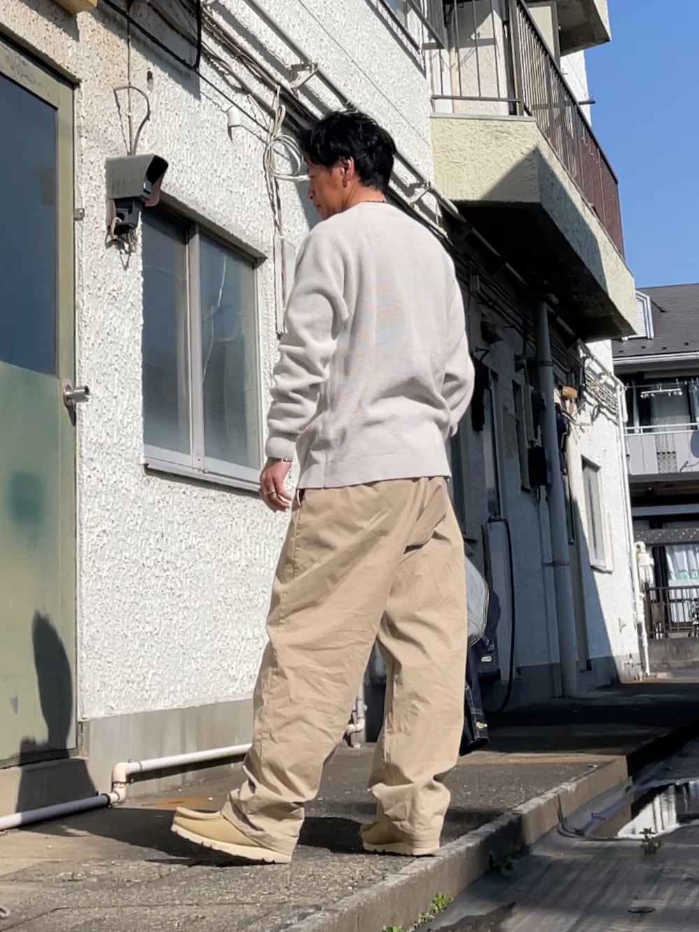 ベージュ系のチノパンツ、ベージュ系のモカシン/デッキシューズ、ベージュ系のニット/セーターを着用したメンズの春コーディネートの2枚目の写真