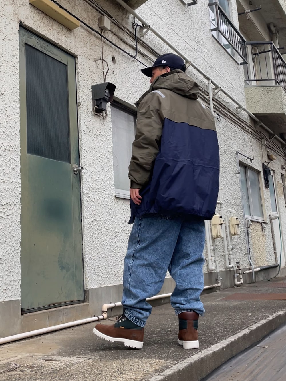 ブラウン系のブーツ、ブルー系のデニムパンツ、グリーン系のポロシャツを着用したメンズの春コーディネートの2枚目の写真