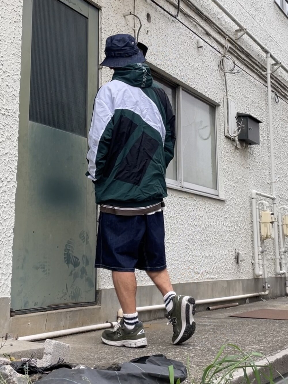 グリーン系のスニーカー、ブルー系のデニムパンツ、グリーン系のマウンテンパーカーを着用したメンズの春コーディネートの2枚目の写真