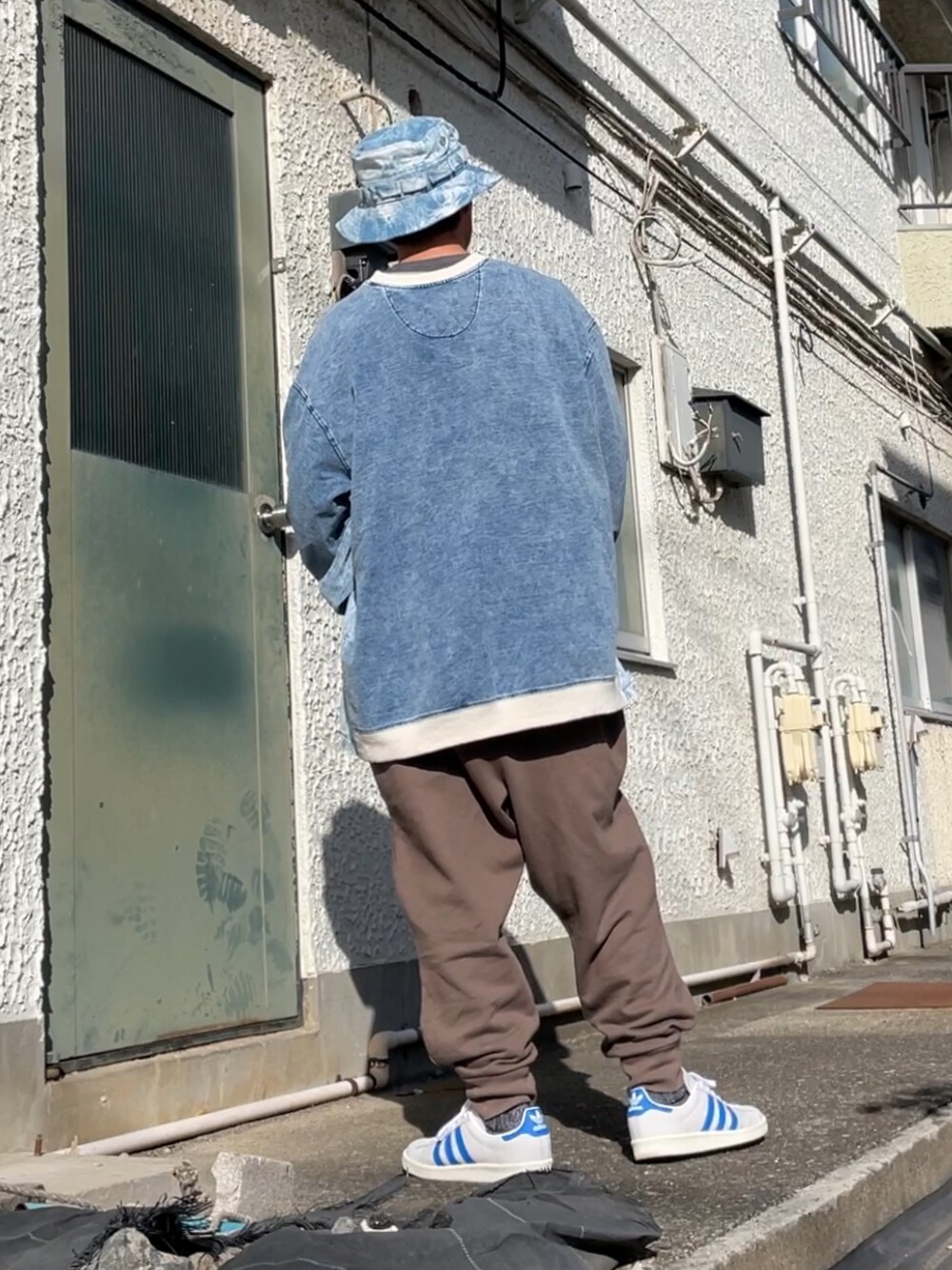 ホワイト系のスニーカー、ブラウン系のパンツ、ブルー系のトップスを着用したメンズの秋コーディネートの2枚目の写真