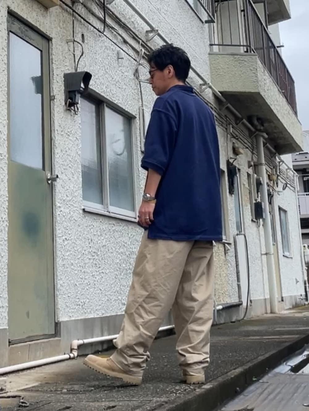ベージュ系のチノパンツ、ブルー系のポロシャツ、ブラウン系のブーツを着用したメンズの夏コーディネートの2枚目の写真