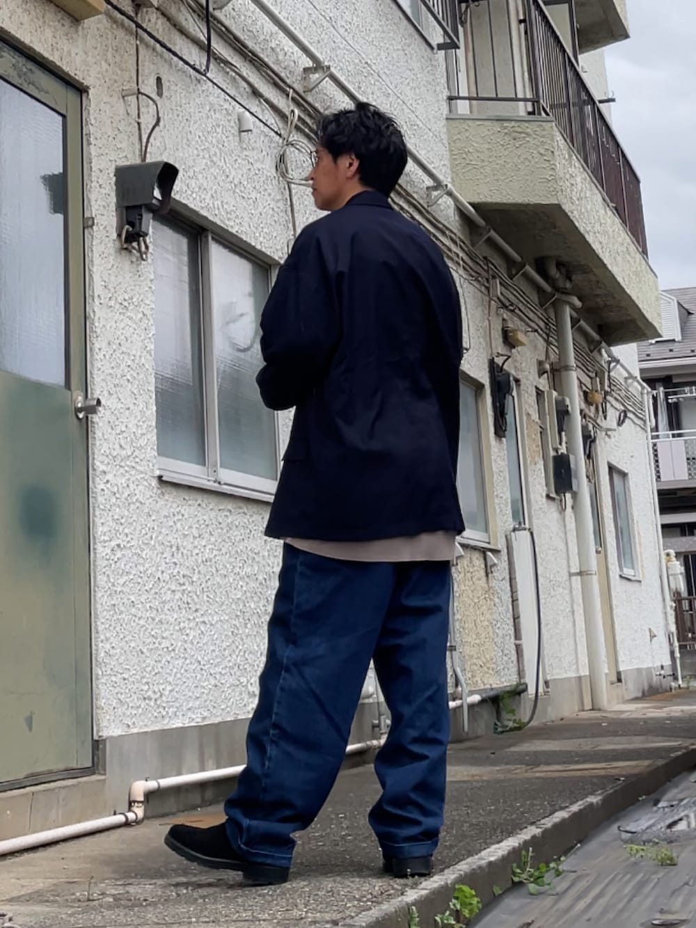 ブラウン系のニット/セーター、ブルー系のデニムパンツ、ブラック系のブーツを着用したメンズの春コーディネートの2枚目の写真